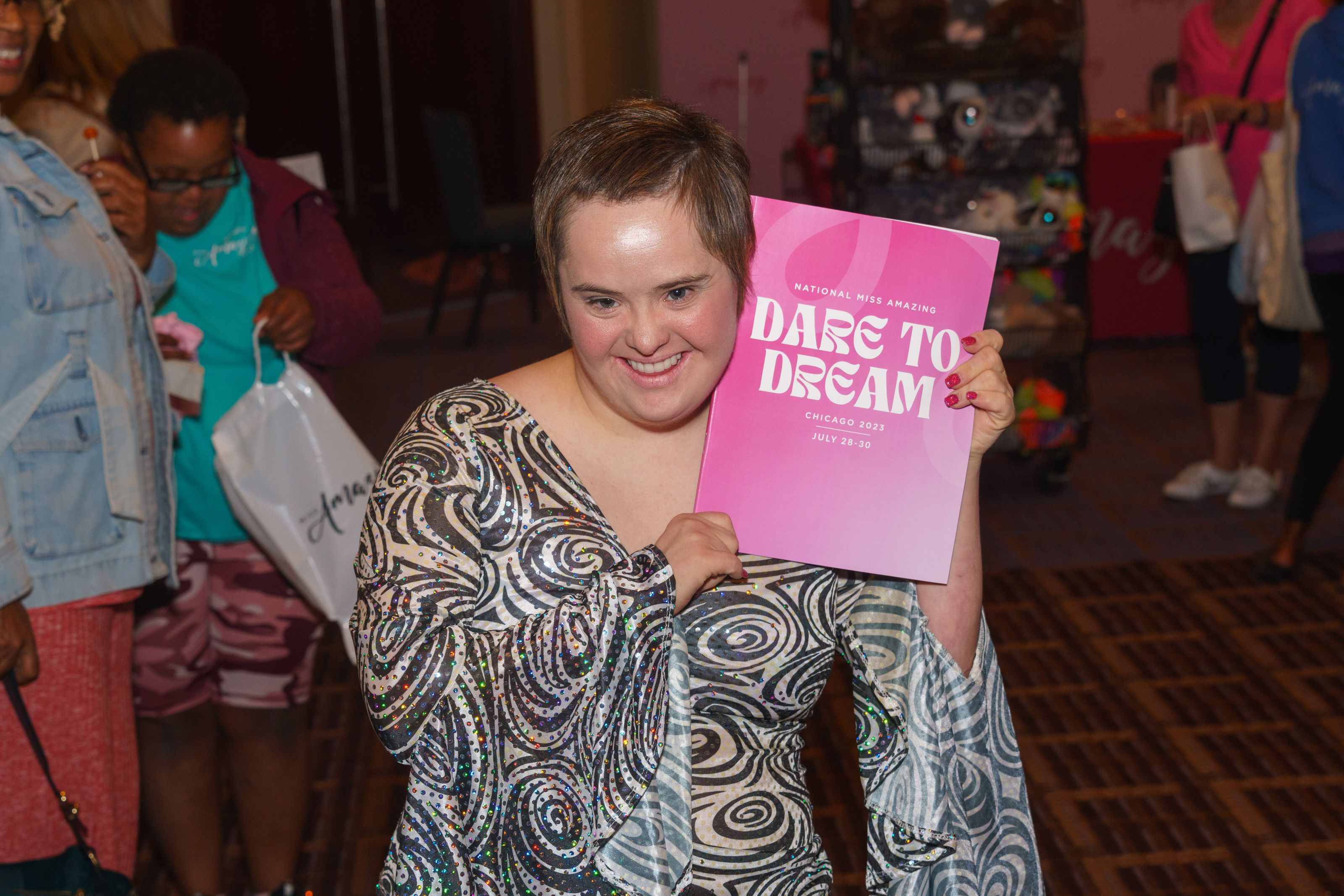 A participant shows off her copy of National Miss Amazing's 2023 program.